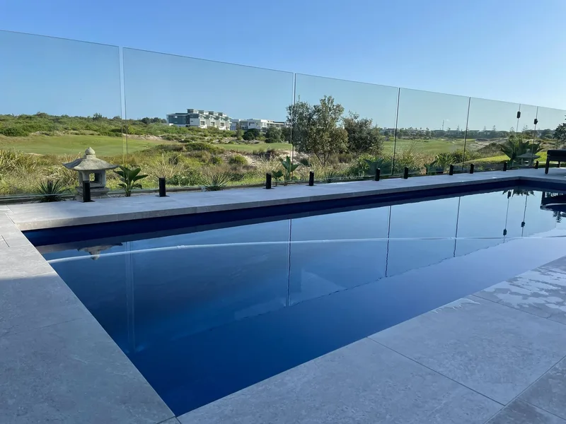 Frameless glass pool fencing overlooking an open landscape, installed by Tuggerah Lakes Glass